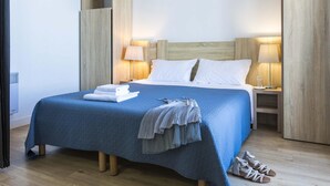 Ein Hotelzimmer mit einem Bett, zwei Nachttischen, einer Lampe, einem Paar Schuhe und einem gefalteten Handtuch.