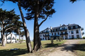 Un edificio grande con diversi balconi e un prato antistante.