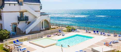 A hotel with a pool area, a staircase, and a view of the sea.