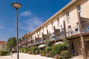 Ein Hotel mit mehreren Balkonen, Sitzgelegenheiten im Freien und blauem Himmel.