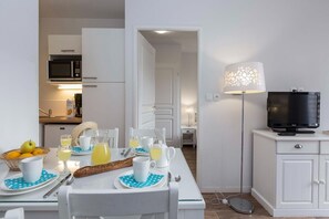 Eine moderne Küche mit Mikrowelle, einem Esstisch mit Frühstücksgebäck und einem Fernseher auf einem Schrank.