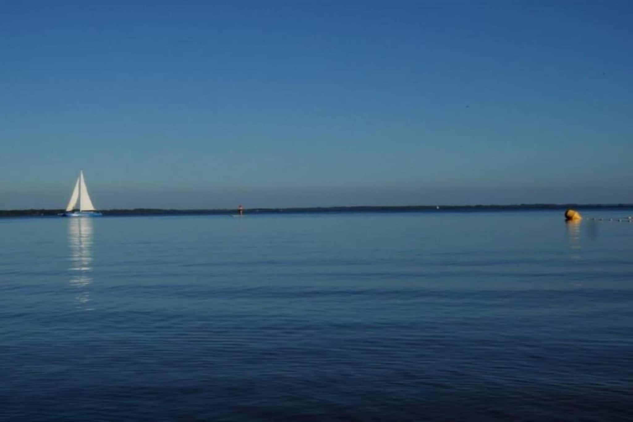 Ett lugnt vattenområde med en segelbåt och bojar.