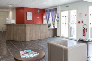 A reception area with a wooden desk, a clock, and a fire extinguisher.