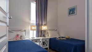 A bedroom with two beds, a nightstand, a lamp, a teddy bear, and a picture on the wall. - Maisonette by Hourtin-Carcans Lake (Hourtin)