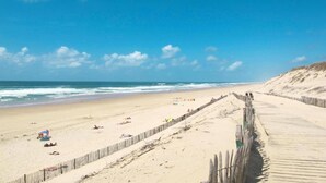 A beach with a wooden boardwalk, sandy shore, and ocean waves. - Maisonette by Hourtin-Carcans Lake (Hourtin)