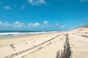 Ein Strand mit Holzsteg, Sandküste und Wellen.