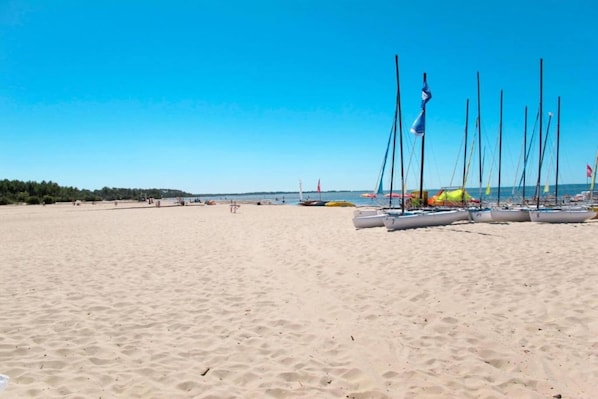 A sandy beach with several sailboats docked near the shore.