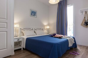 A bedroom with a bed, bedside lamps, a window with curtains, and a door. - Maisonette by Hourtin-Carcans Lake (Hourtin)