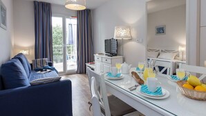 Een moderne hotelkamer met een bank, eettafel en ontbijt opstelling.