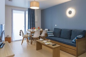 A modern living room with a sofa, coffee table, and dining table set.