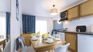 A compact kitchen with a dining area, a microwave, a coffee maker, and a dishwasher. - Apartment in Trégastel near the Beach (Trégastel)