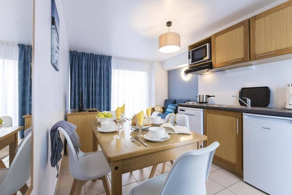 A compact kitchen with a dining area, a microwave, a coffee maker, and a dishwasher.