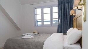 A bedroom with a bed, a window, and a nightstand. - Apartment in Trégastel near the Beach (Trégastel)