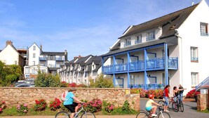 A residential street with houses, a stone wall with flowers, and people cycling. - Apartment in Trégastel near the Beach (Trégastel)