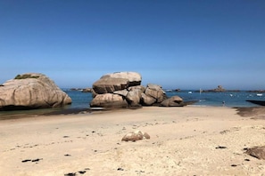 Una playa con rocas grandes y agua azul cristalina.