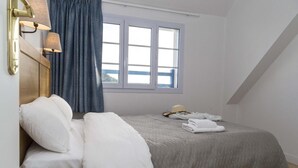 Ein Schlafzimmer mit Bett, Kissen, einem Fenster und einer Lampe.