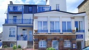 A multi-story building with a blue balcony, a stone facade, and a sign for 'Odalys Accueil'. - Apartment in Trégastel near the Beach (Trégastel)