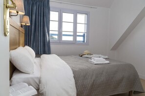 Ein Schlafzimmer mit Bett, Kissen, einem Fenster und einer Lampe.