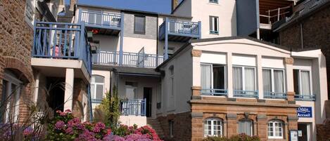 A hotel with a stone facade, multiple balconies, and a sign indicating it is an 'Accueil' hotel.