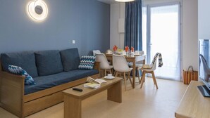 A modern living room with a sofa, coffee table, and dining area. - Apartment in Trégastel near the Beach (Trégastel)
