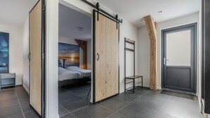 A modern bedroom with a sliding door, a bed, a small table, and a ladder. - Holiday Home in Netherlands Pond View (Baarle-Nassau)