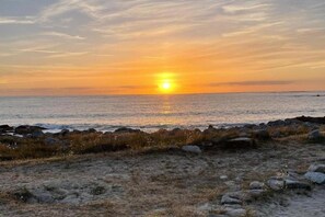A sunset over a rocky shoreline with waves.