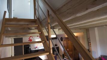 A wooden staircase leading to an upper floor with a kitchen area visible below.