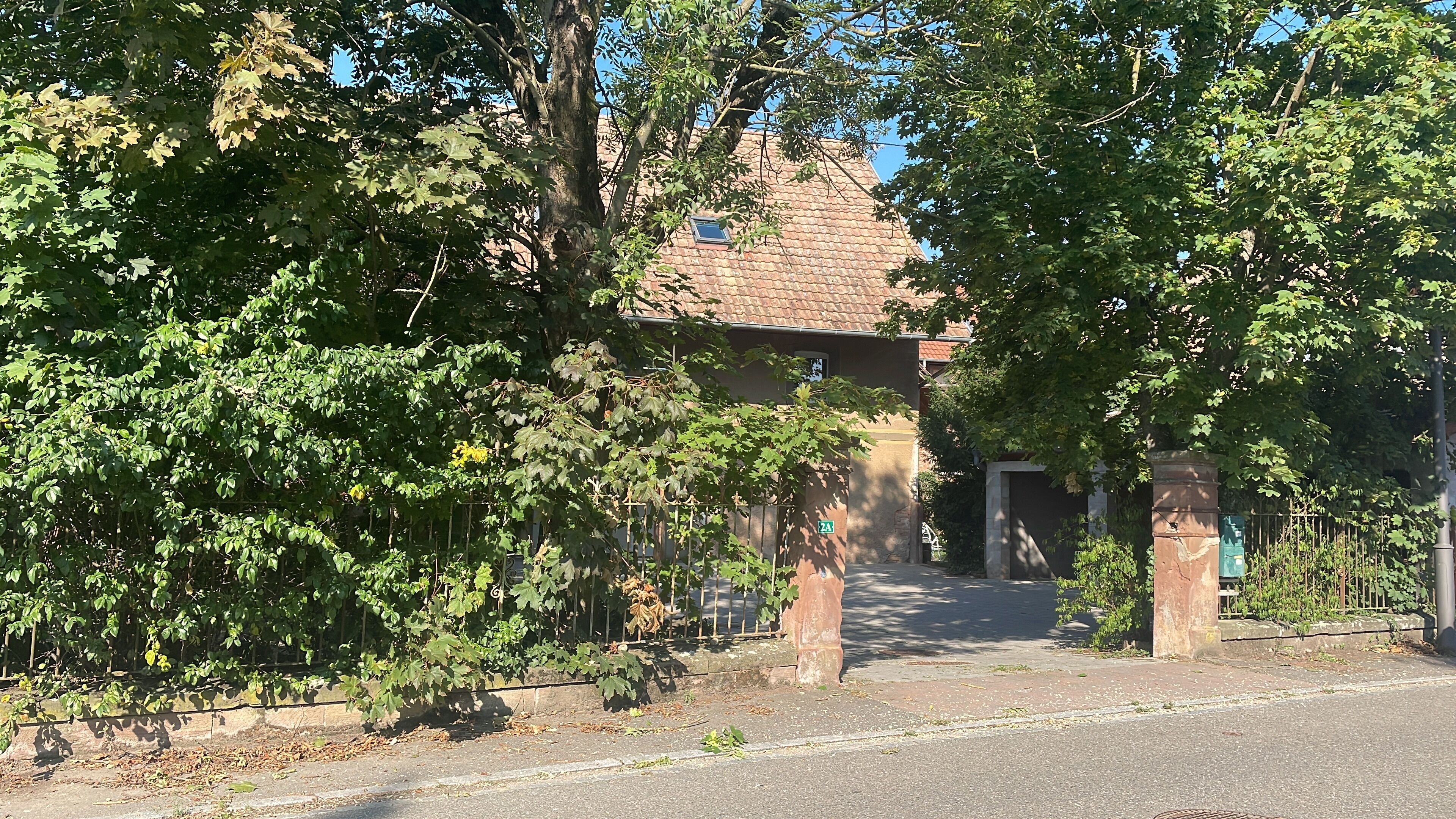 A residential street with a house, a gate, and a fence.