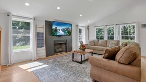 A spacious living room with a fireplace, a large flat-screen TV, and a sofa. - Adventures at Aspen Way: WHOLE HOME & 7 ACRE RETREAT (Rockbridge)