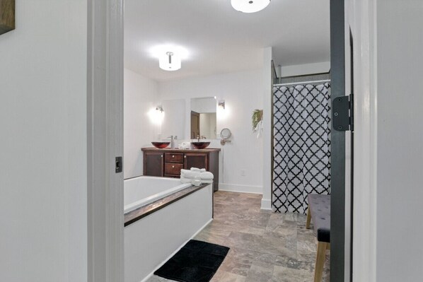 A modern bathroom with a bathtub, a vanity with a mirror, and a sink.
