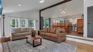 A spacious living room with a large sofa set, a coffee table, and a dining area with a wooden table and chairs. - Adventures at Aspen Way: WHOLE HOME & 7 ACRE RETREAT (Rockbridge)
