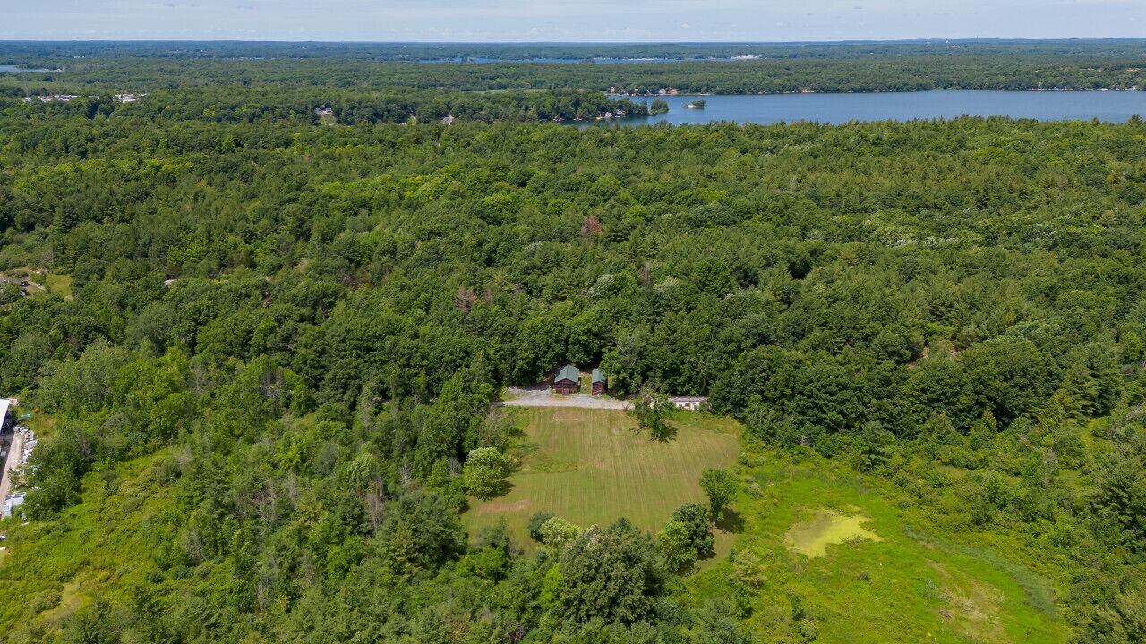 An aerial view of a forested area with a small clearing and a building.