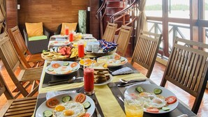 Zona pranzo con arredi in legno, un buffet con diversi piatti e una scala che conduce a una zona all'aperto.
