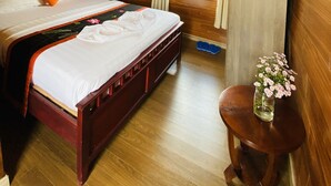 Una camera in legno con un letto, una ventola, una finestra con tende e un tavolino con un vaso.