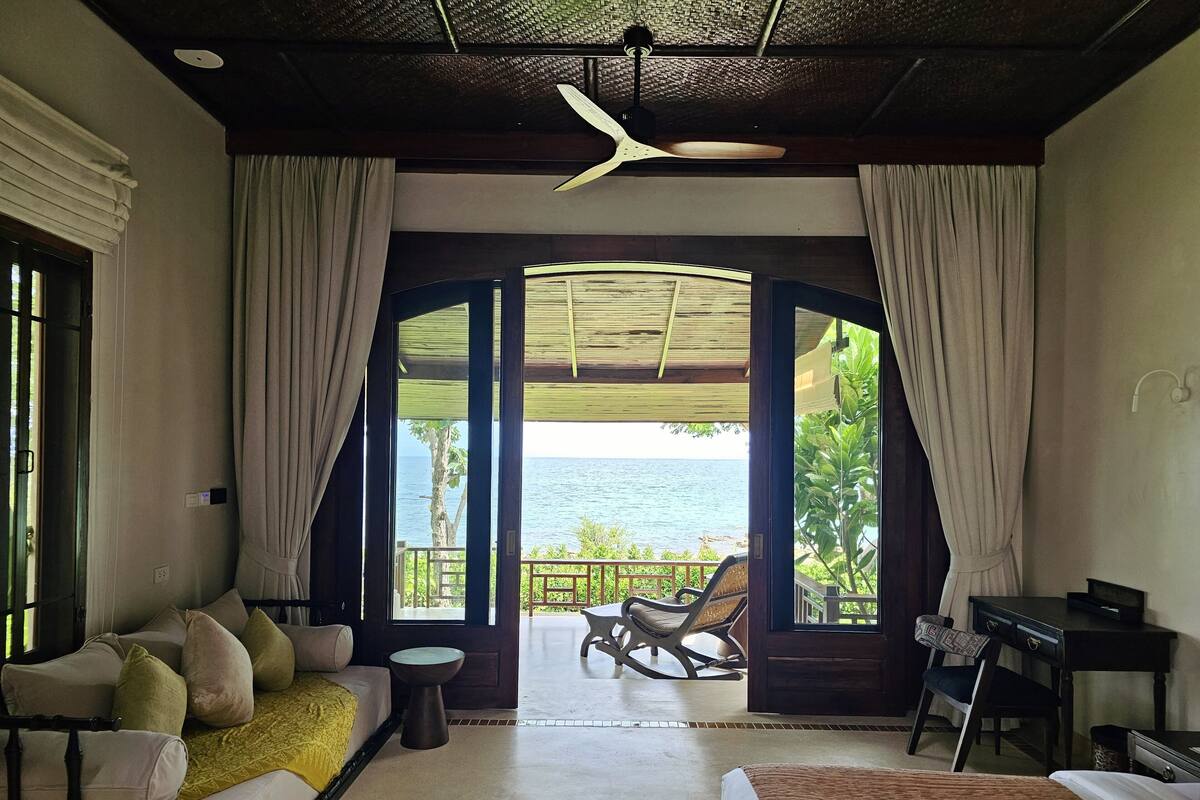 A hotel room with a bed, a sofa, a desk, and a view of the ocean.