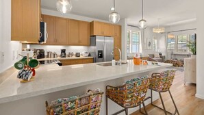 Una cocina moderna con armarios de madera, electrodomésticos de acero inoxidable y una isla central con taburetes de bar.