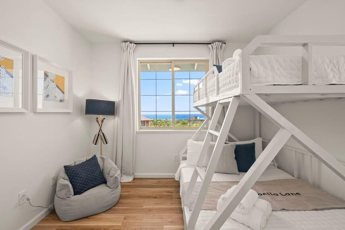 A bunk bed room with a view of the ocean, a bean bag chair, and a lamp.