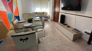 A dining area with a glass table, chairs, and a sofa in the background.