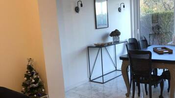 Un coin repas avec une table et des chaises, un petit sapin de Noël et une fenêtre donnant sur un paysage verdoyant.