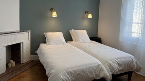 Ein Schlafzimmer mit zwei Betten, einem Kamin und zwei Wandleuchten.