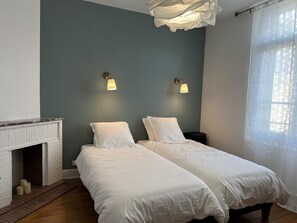 Un dormitorio con dos camas, una chimenea y dos lámparas de pared.
