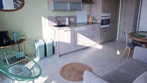 Uma cozinha moderna com forno embutido, área de jantar com mesa redonda e uma cadeira verde.