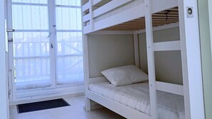 Quarto com beliche e porta de vidro deslizante para uma varanda.