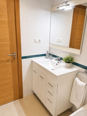 A bathroom with a white sink, wooden door, and a mirror.