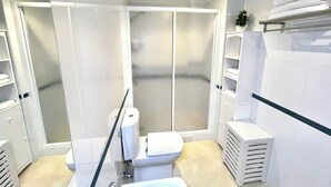 A modern bathroom with a shower, toilet, and sink.