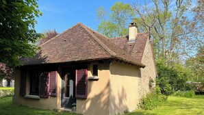 A small, single-story house with a sloped roof and a chimney. It has a front door with a small porch and shutters. - La Maison du Moulin (Saint-Georges-sur-Eure)