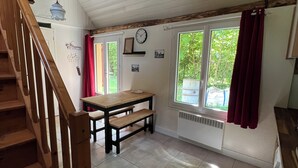 A kitchen with a wooden staircase, a dining table, and a window with curtains. - La Maison du Moulin (Saint-Georges-sur-Eure)