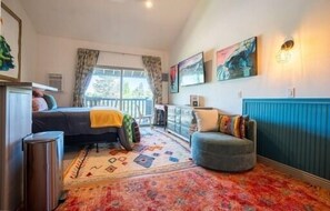 A bedroom with a bed, a chair, a radiator, and a window with curtains.