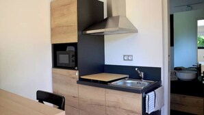 Una cucina compatta con forno a microonde, lavello e mobili in legno.
