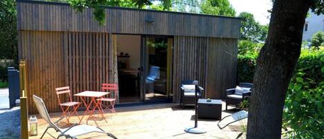 A modern outdoor patio with wooden flooring, metal-framed chairs, and a table.